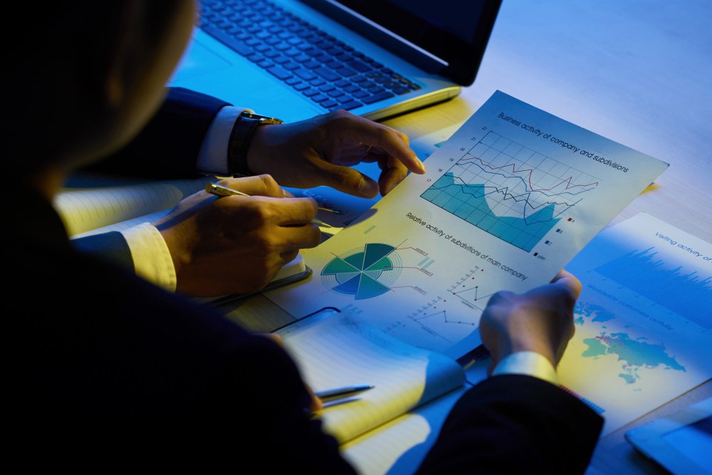 Manager analysing business activity charts and cost breakdowns on paper — SAP Business One cost-effectiveness for Indian SMEs